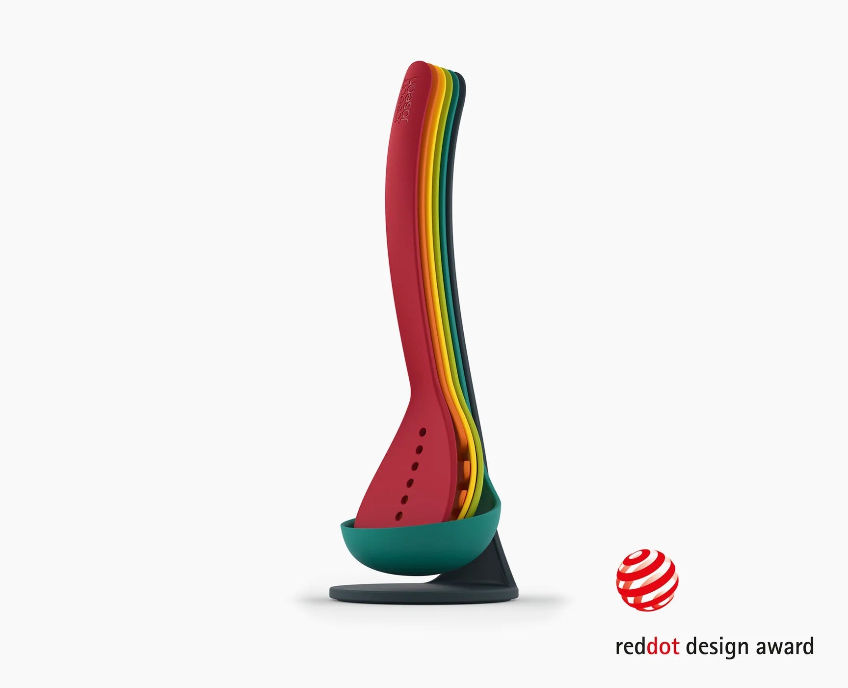 Red silicone utensil with rainbow stripe handle on a teal magnetic stand base.