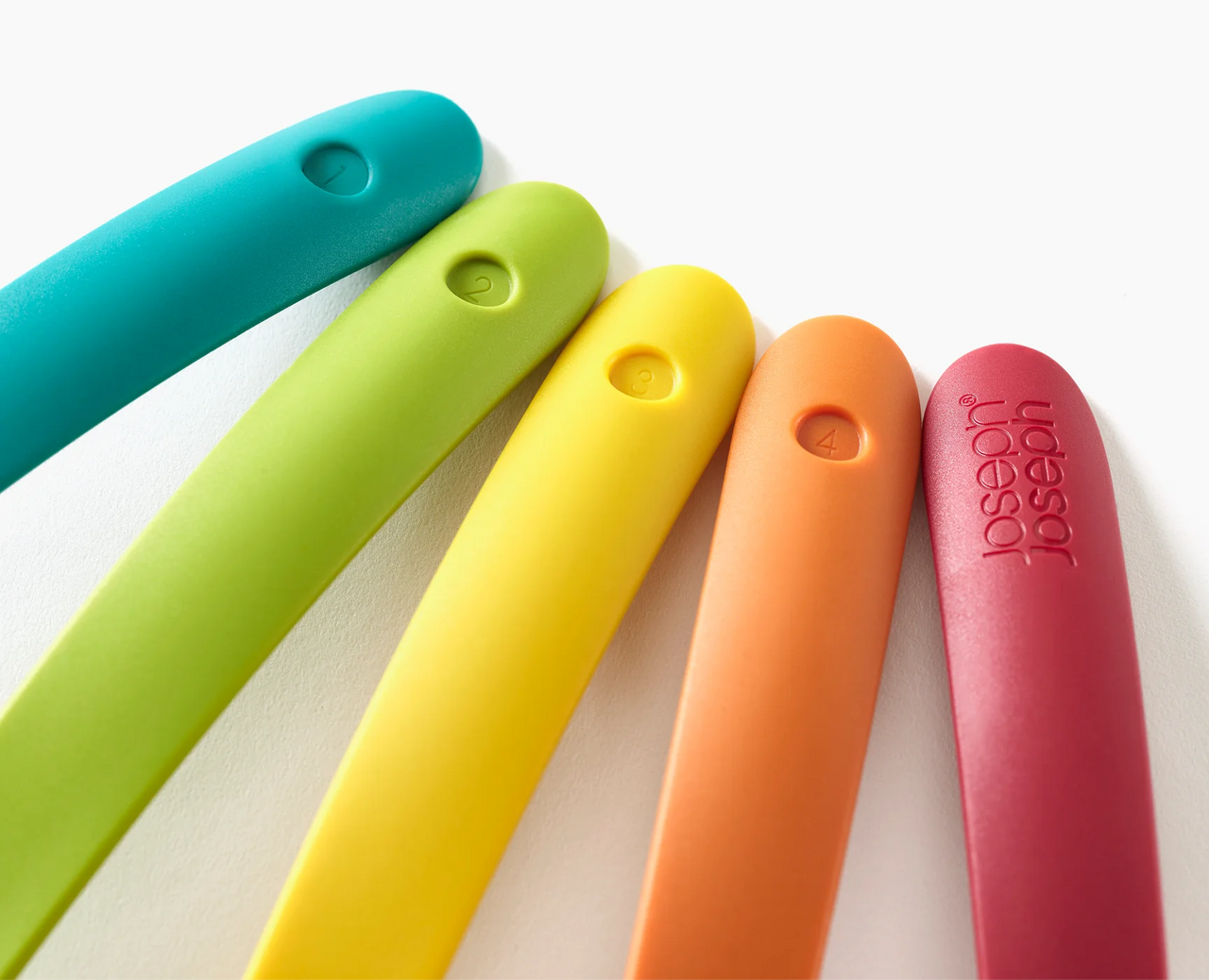 Close-up of five multicolour silicone utensil handles, showing circular embossed grip details.