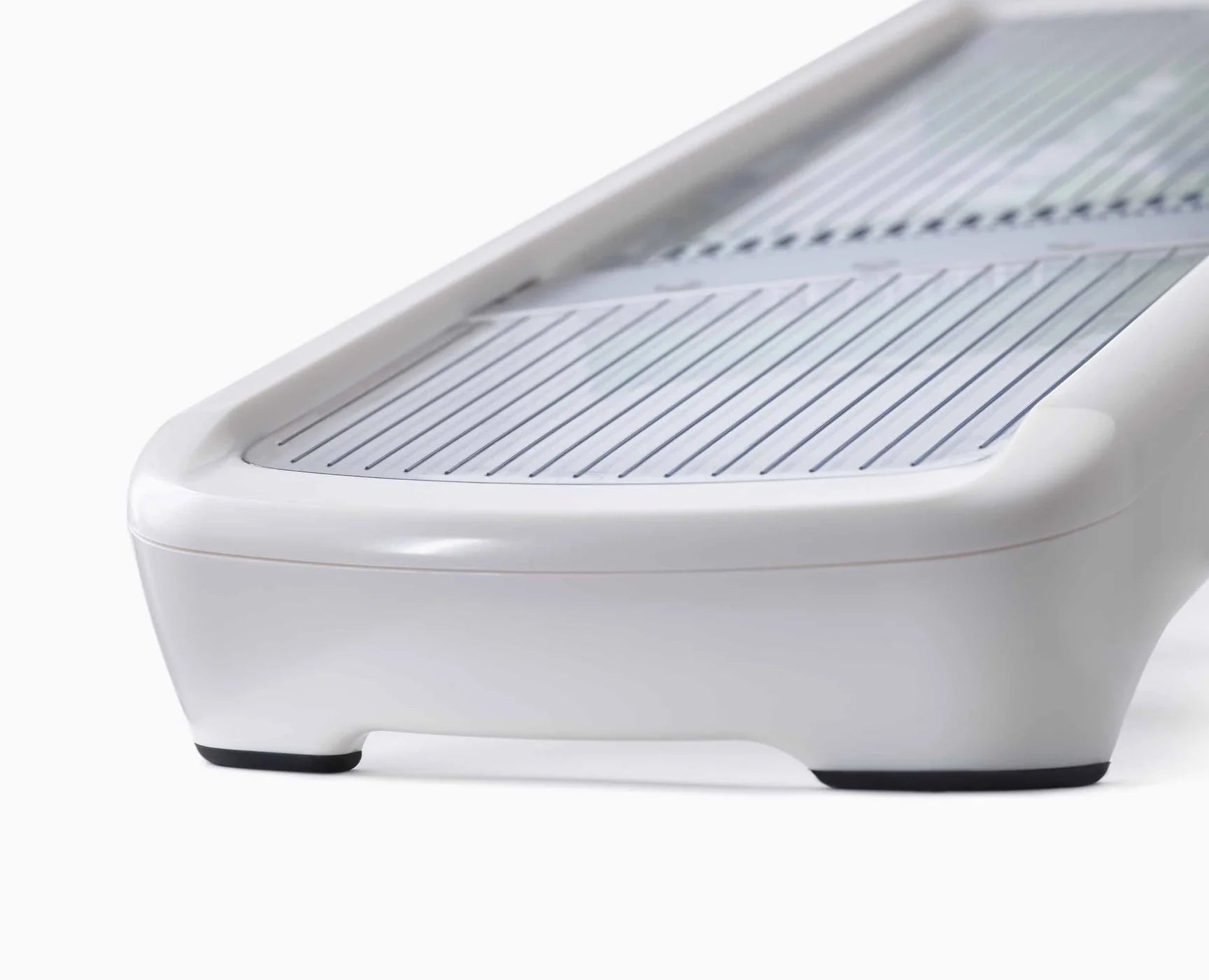 White mandoline base with ridged slicing tray and front support foot
