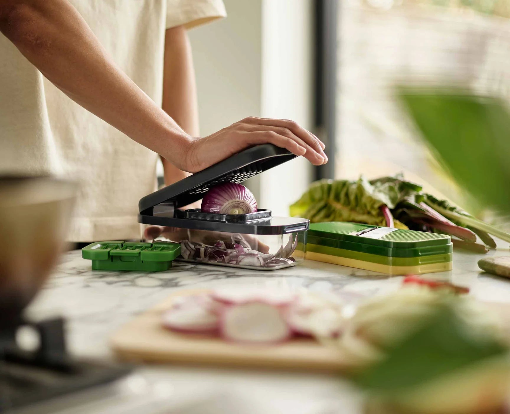 Compact food prep chopper set in use with hand operating lid over clear container