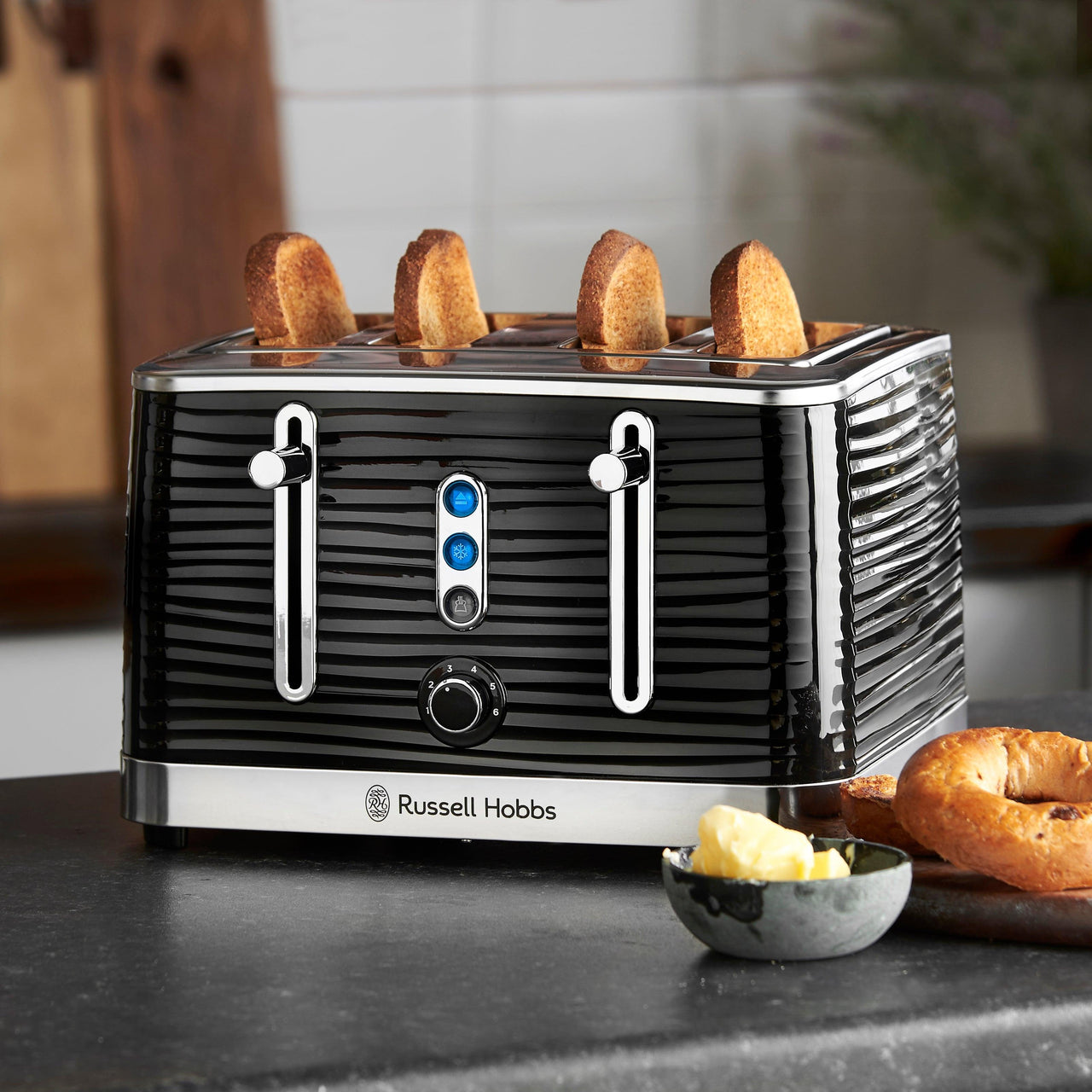Black 4-slice toaster on countertop with bread slices in the slots
