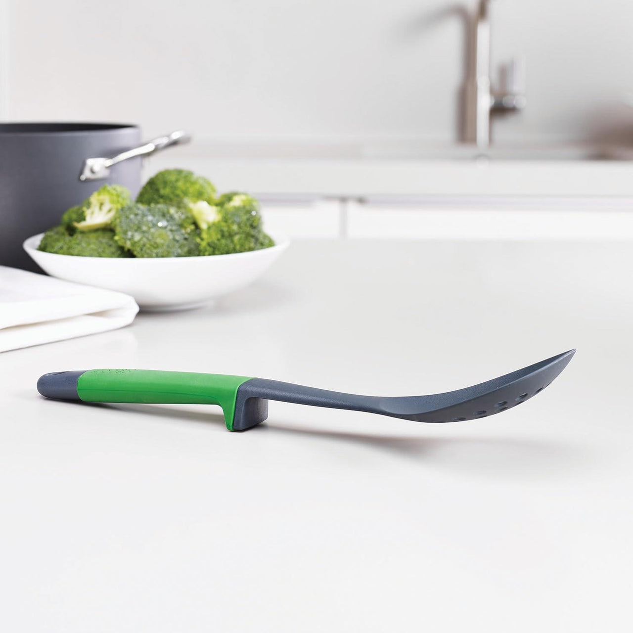 Kitchen slotted spatula with green handle and dark gray edge, utensil set piece
