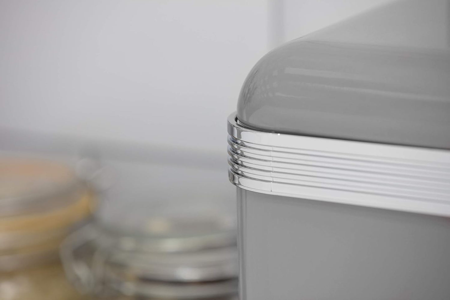 Close-up of grey canister lid edge with silver ribbed trim and metal knob