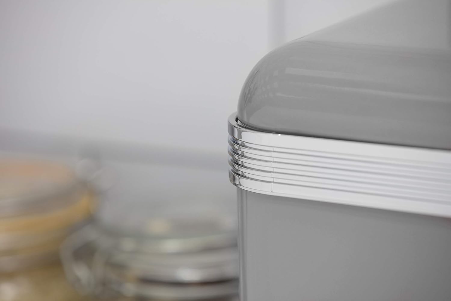 Close-up of grey canister lid edge with silver ribbed trim and metal knob