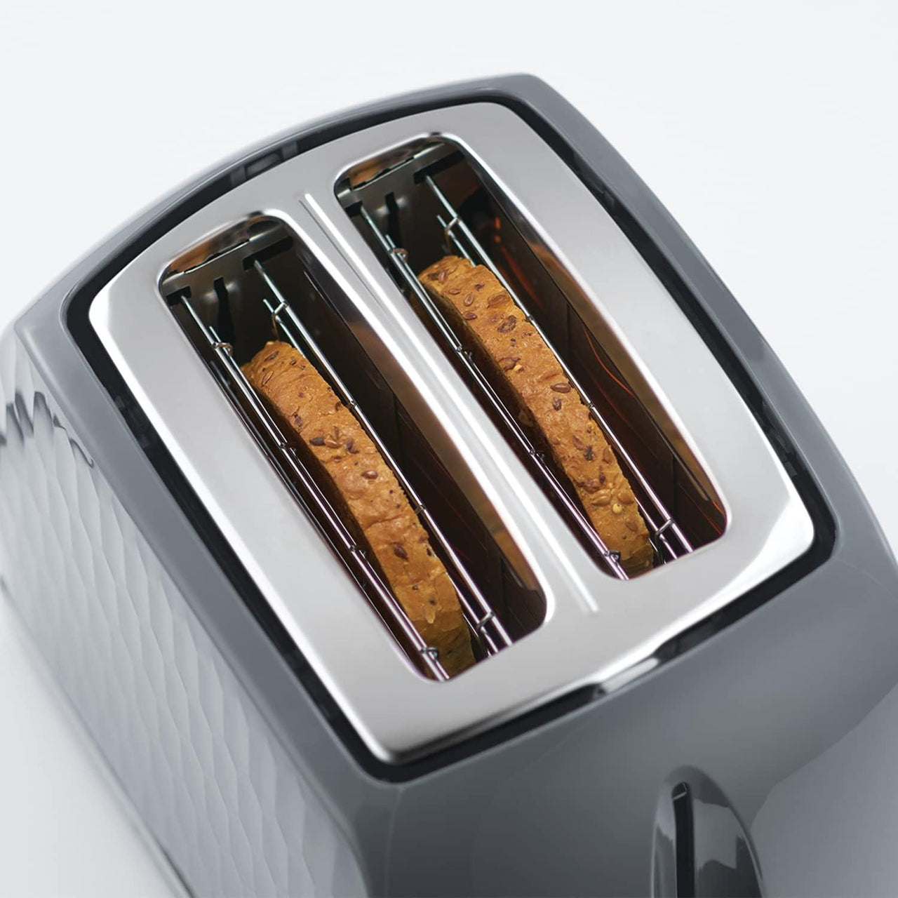 Grey 2-slice toaster with two heating slots, showing browned toast inside