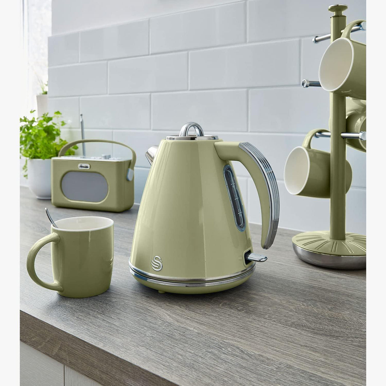 Green retro jug kettle on kitchen counter with matching mugs
