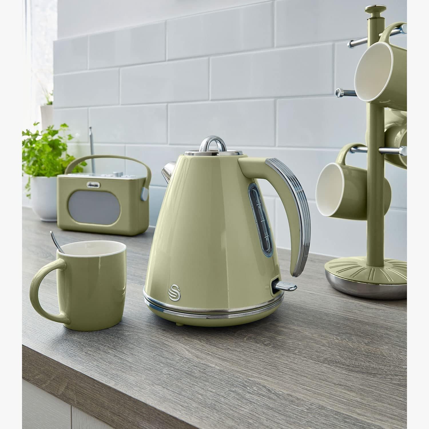 Green retro jug kettle on kitchen counter with matching mugs