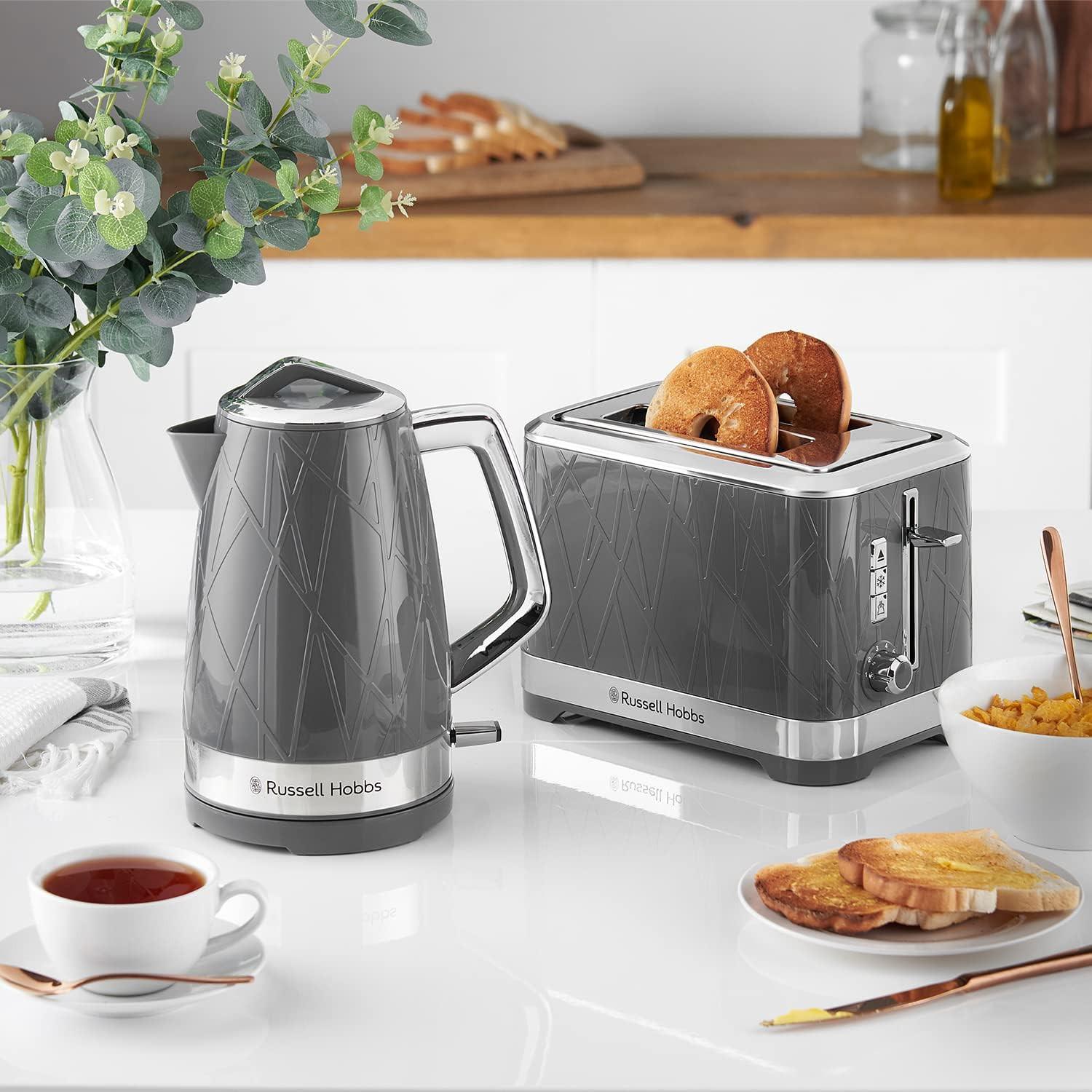 Grey 2-slice toaster with toast in the open slots on a kitchen countertop