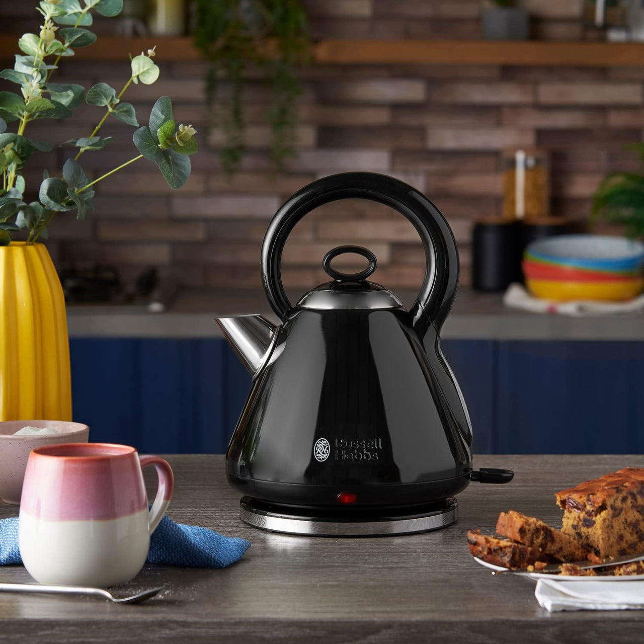 Black pyramid electric kettle with anti-drip spout, resting on base