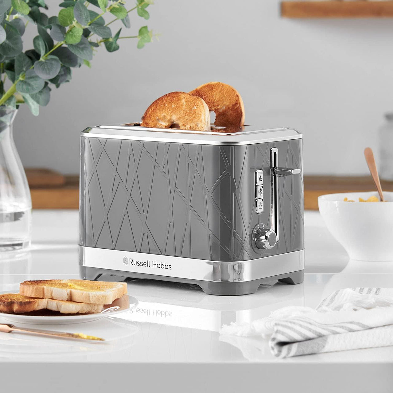 Grey 2-slice toaster with toast in the open slots and chrome control lever