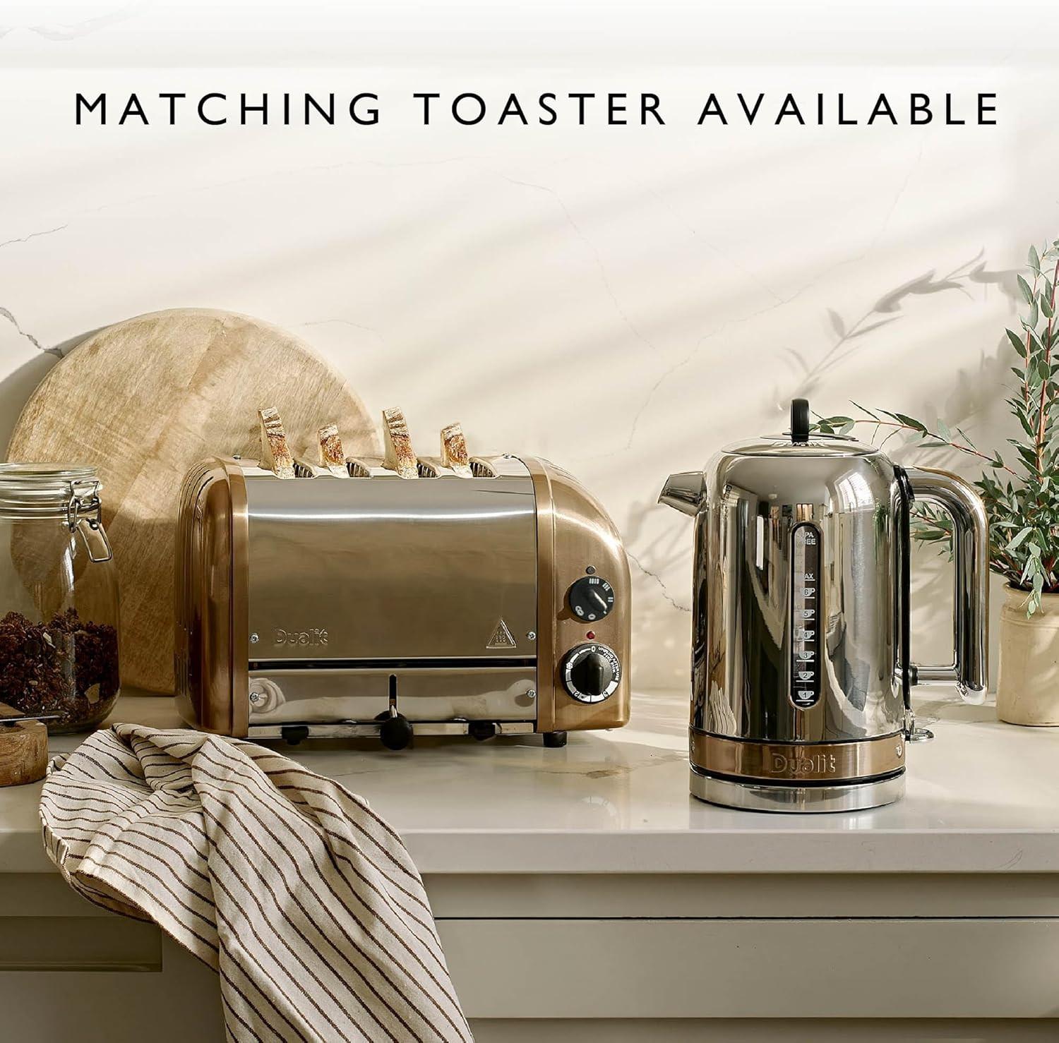 Stainless steel kettle with copper trim on countertop, with lid and handle visible