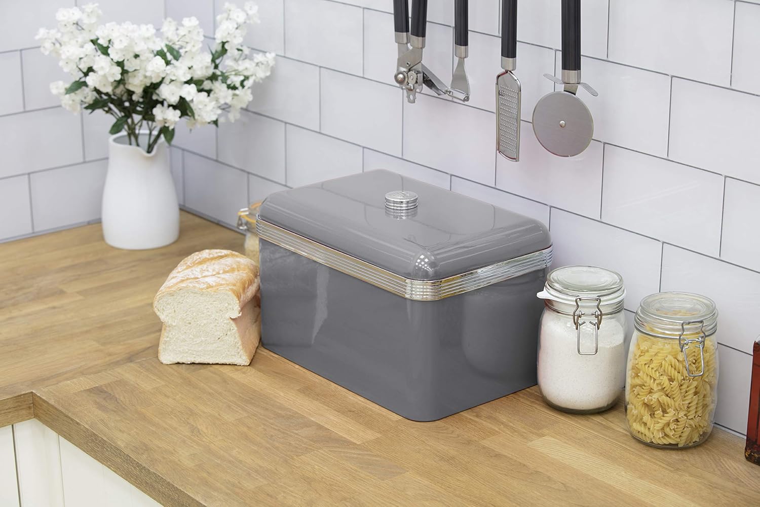 Grey retro bread bin with silver ribbed trim beside kitchen jars and bread pieces