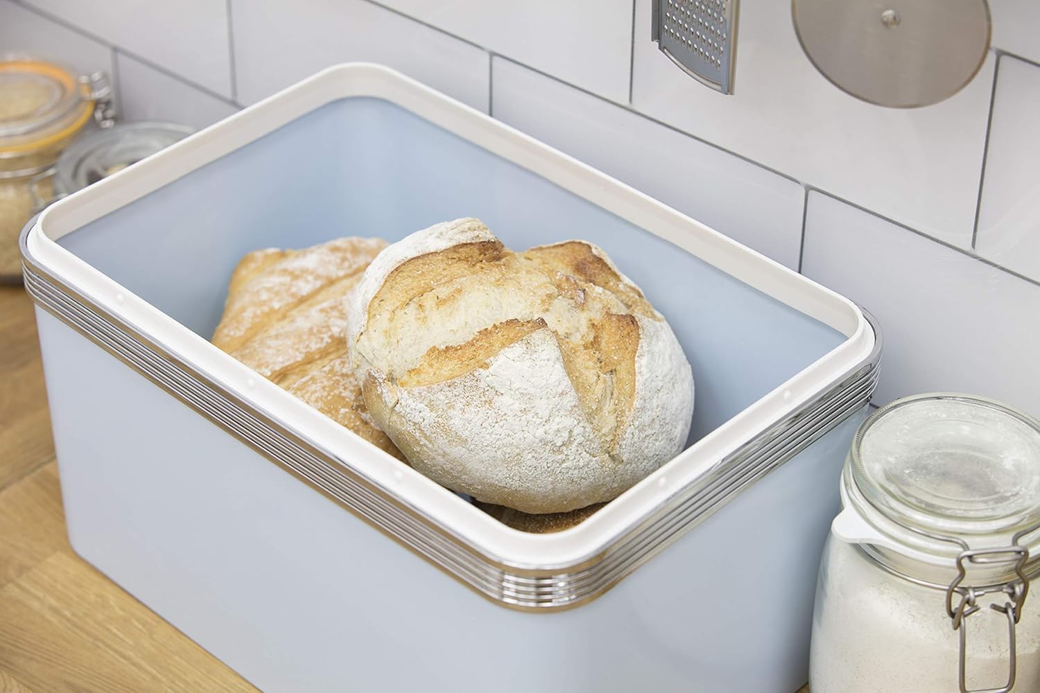 Blue bread bin open with loaf bread inside and chrome ribbed trim