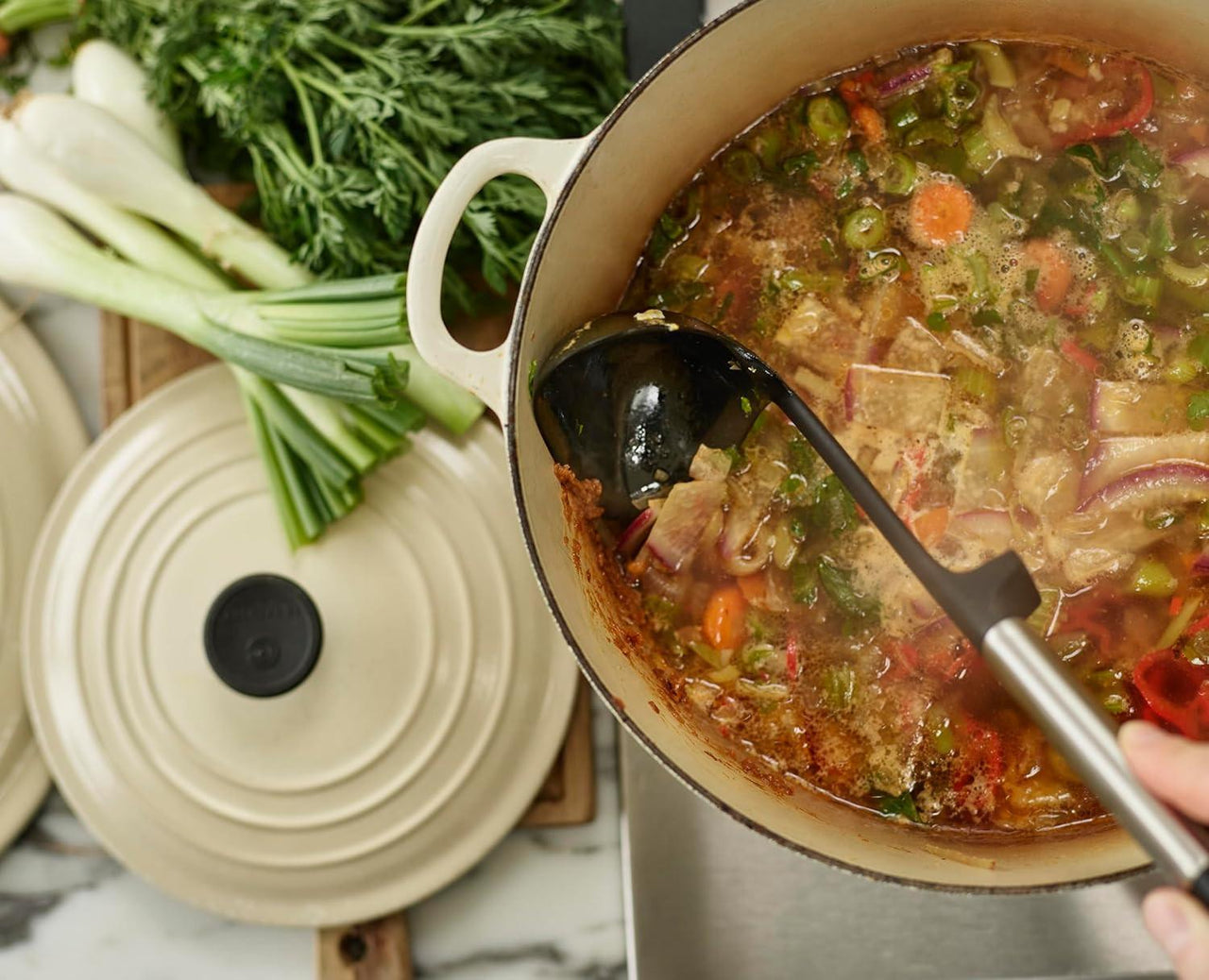 Black silicone ladle stirring stew in a cooking pot