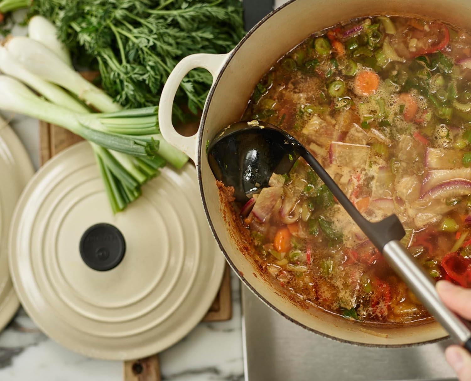 Black silicone ladle stirring stew in a cooking pot
