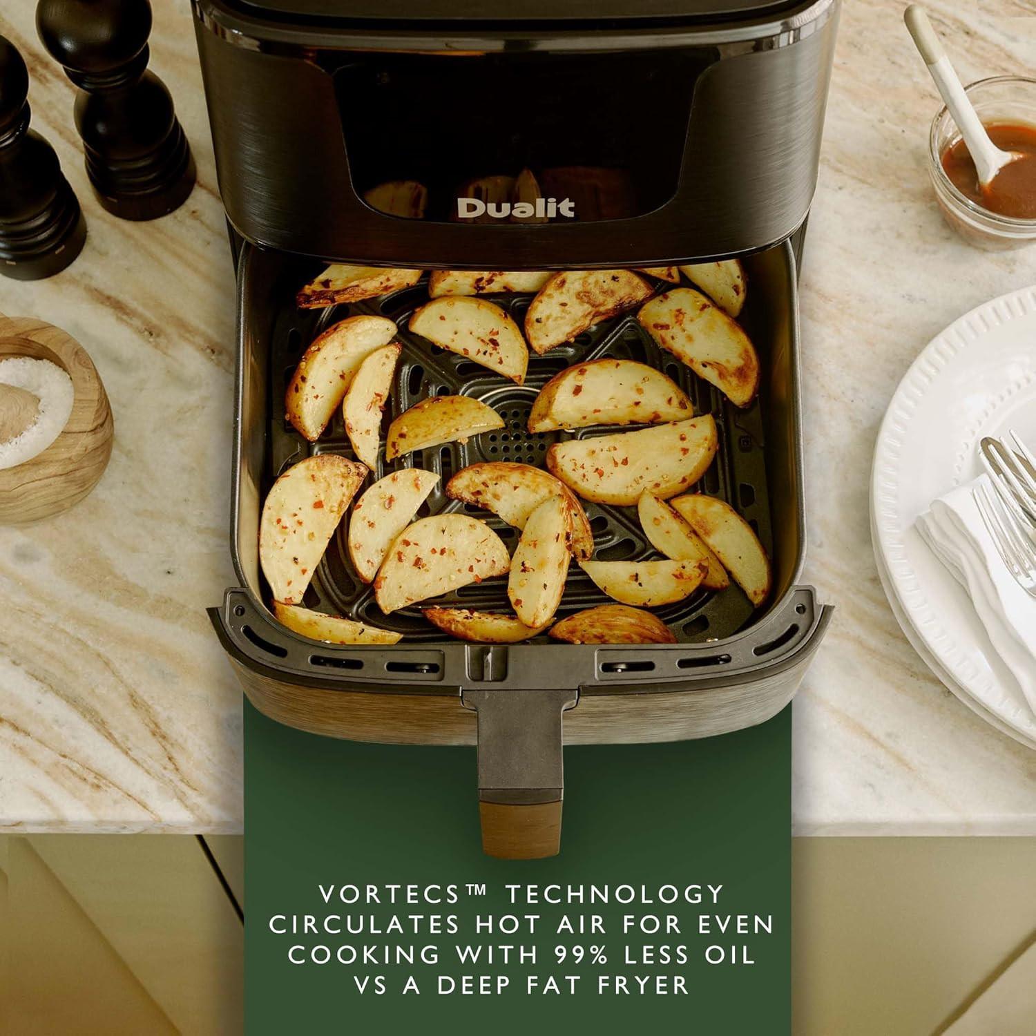Open black Dualit air fryer drawer with seasoned potato wedges inside.