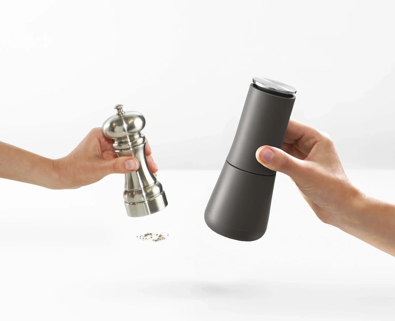 Dark grey non-spill salt and pepper mill held near silver whisk