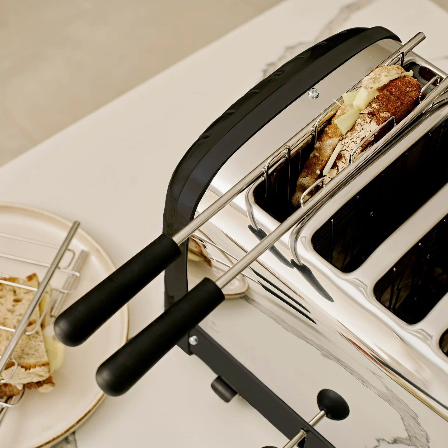 Dualit 4-slice toaster with toast in the stainless steel slots and front levers