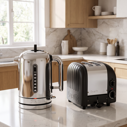 A stainless steel electric kettle and a black and silver toaster sit on a white marble kitchen countertop in a modern kitchen with light wood cabinets.