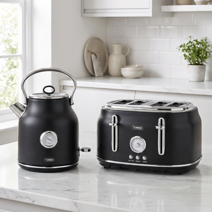 A black electric kettle and a four-slot toaster with silver handles and trim sit side by side on a white marble kitchen countertop.