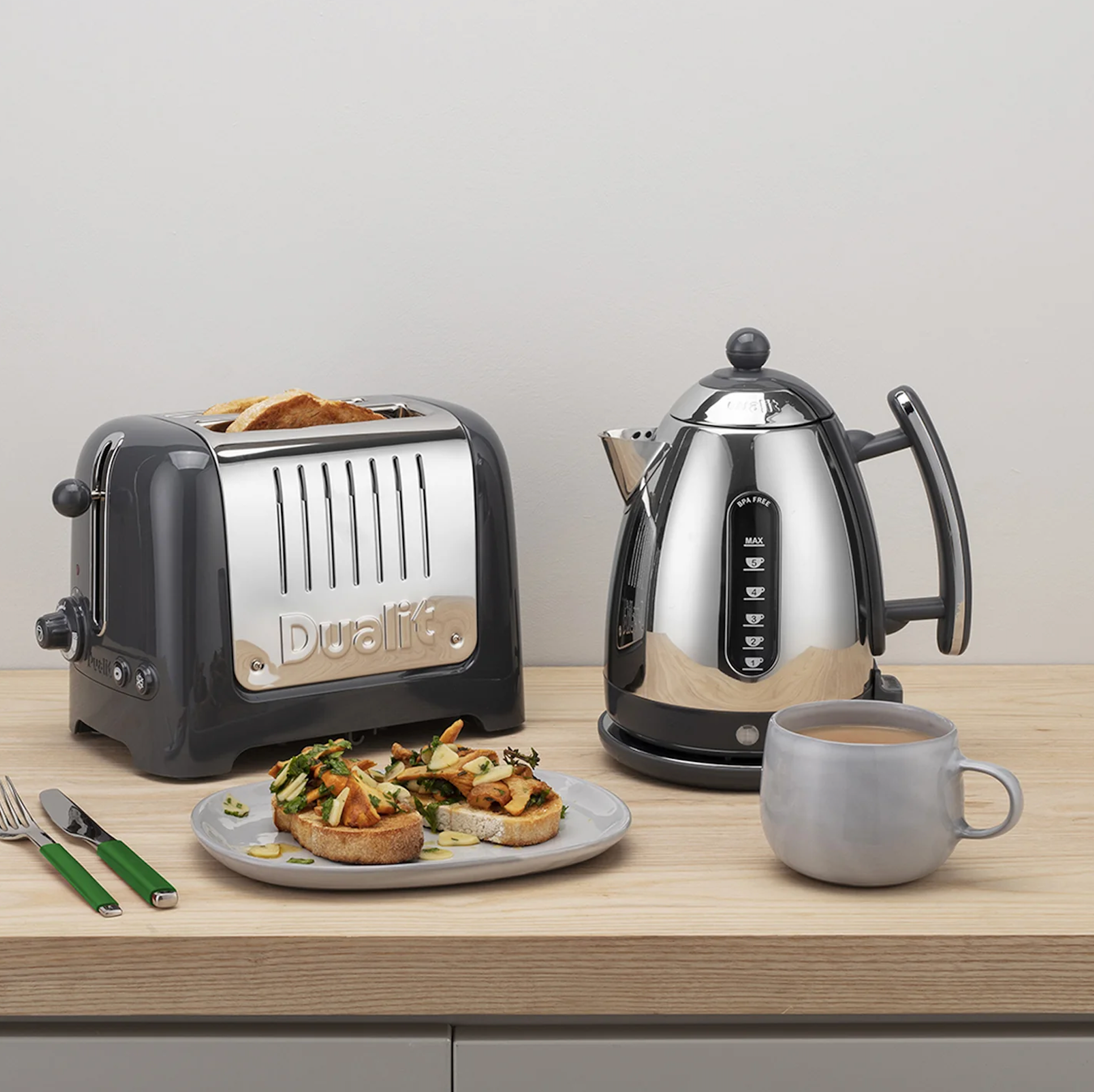Grey 2-slice toaster next to kettle on tabletop, showing front slots and lever