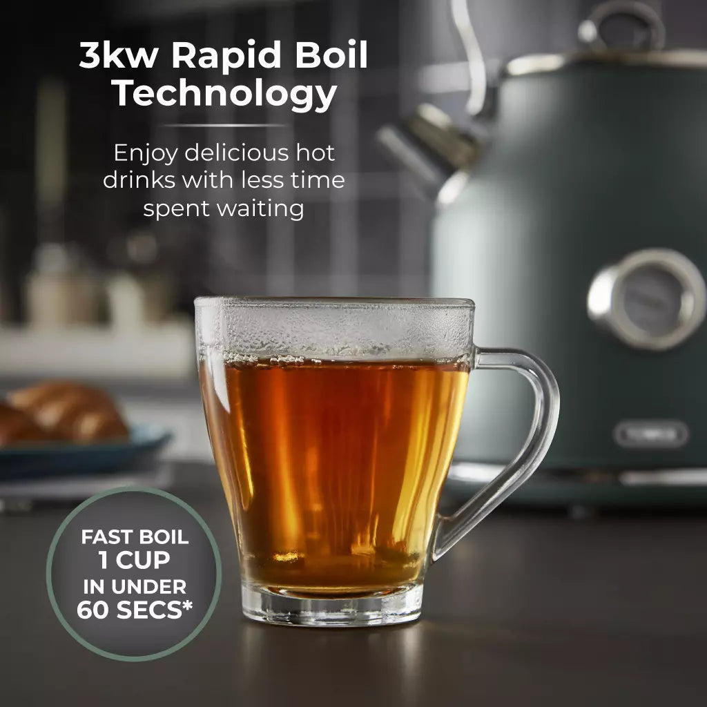 Forest green kettle pouring hot tea into clear glass mug on a countertop