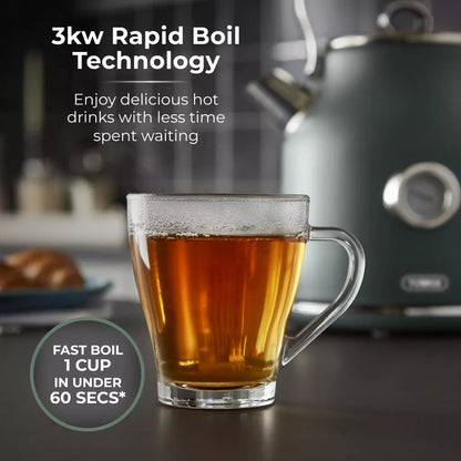 Forest green kettle pouring hot tea into clear glass mug on a countertop