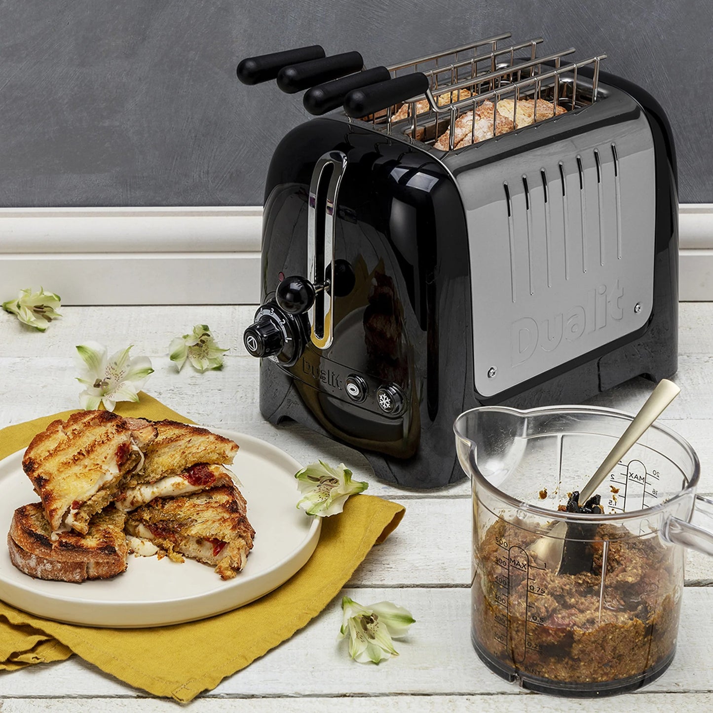 Black Dualit Lite toaster with toast and chrome kettle beside a serving bowl