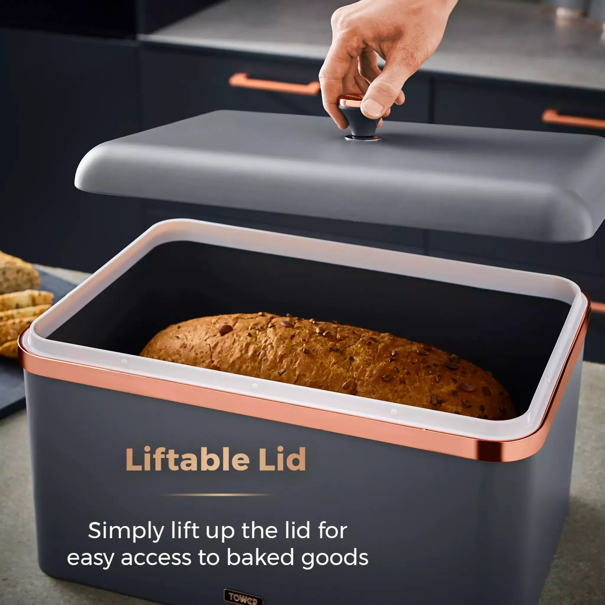 Hand lifting grey bread bin lid to access loaf, with rose-gold trim