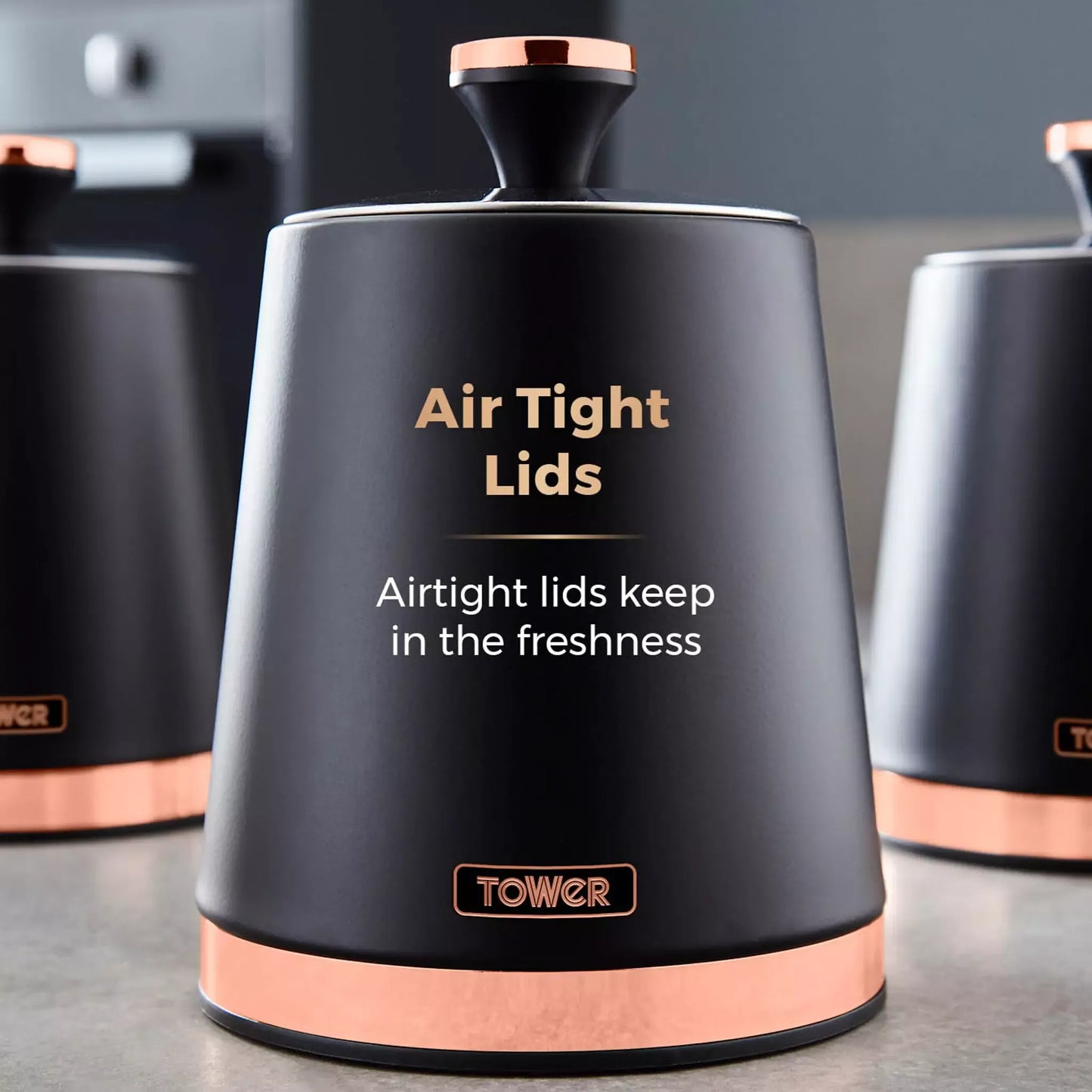 Black kitchen canister with rose-gold base ring and rose-gold lid knob