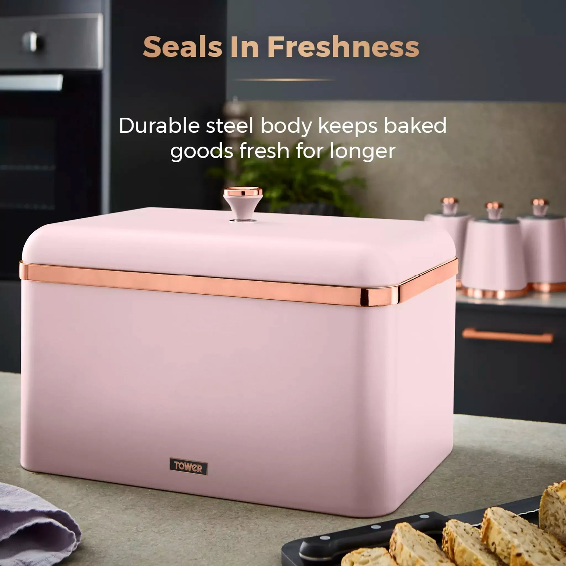 Marshmallow pink bread bin with copper handle, closed lid; countertop storage for baked goods.