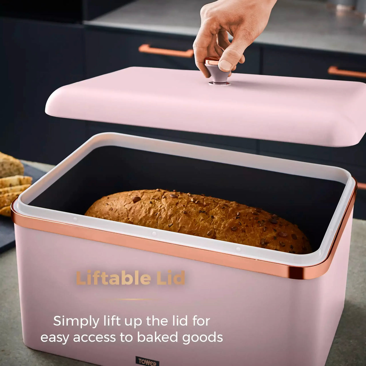 Marshmallow pink bread bin with liftable lid, copper trim; contains baked loaf inside.