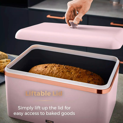 Marshmallow pink bread bin with liftable lid, copper trim; contains baked loaf inside.