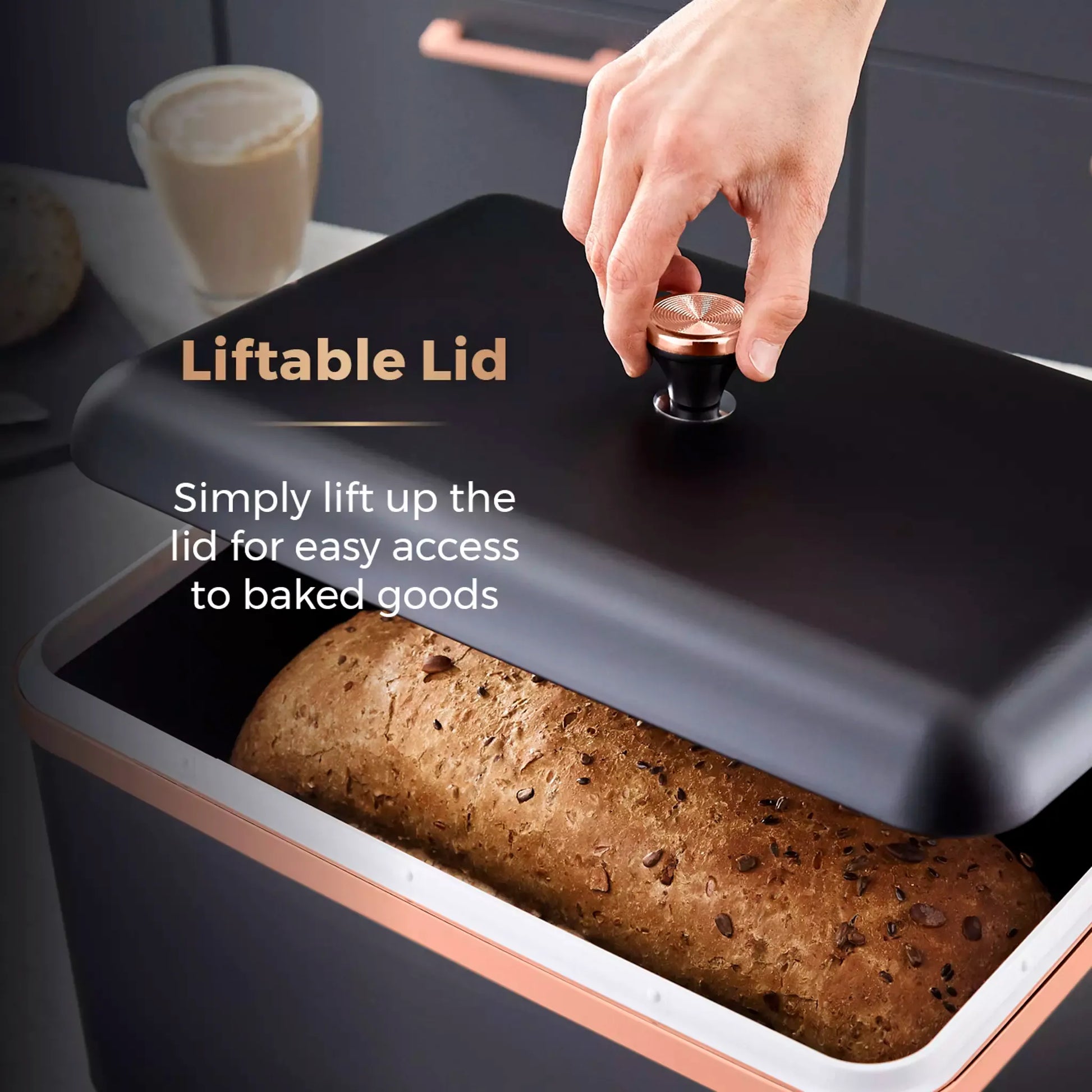 Black bread bin with liftable lid being lifted by hand, loaf inside