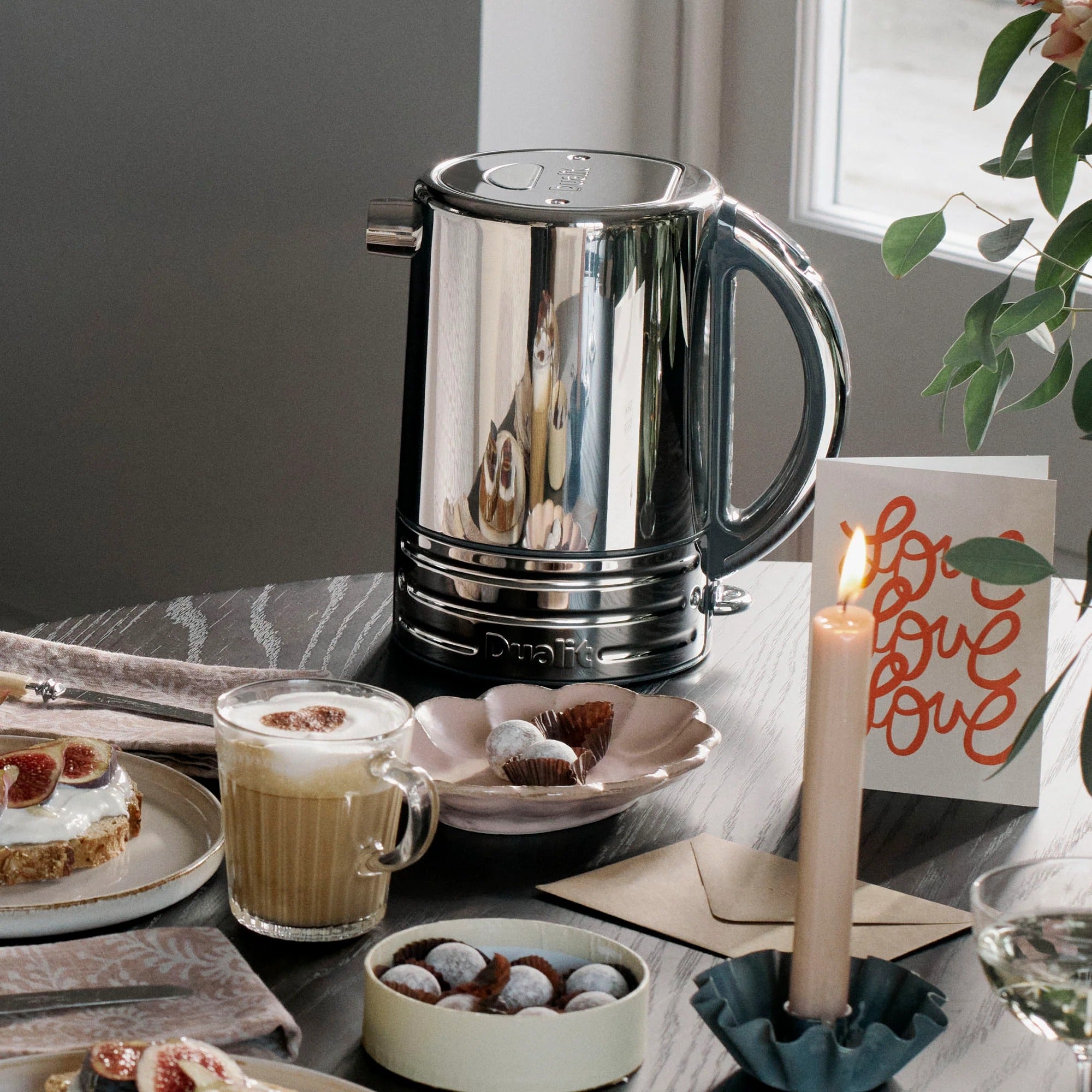 Chrome kettle on breakfast table with pastries and cups, countertop appliance